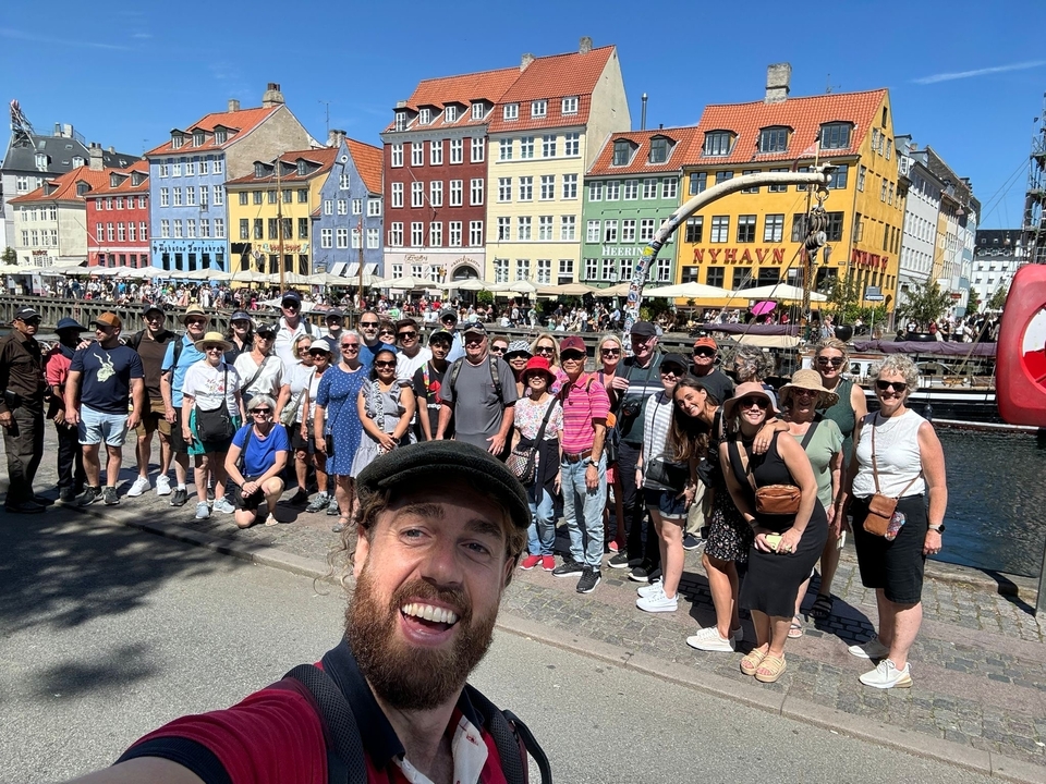 Groupe de touristes posant le long de bâtiments colorés au bord du canal.