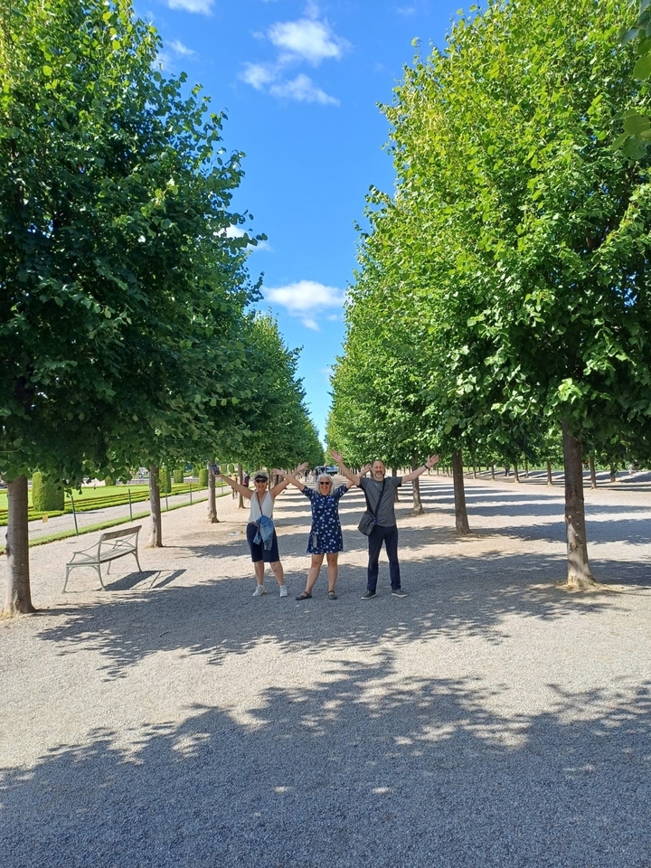 Trois personnes posant joyeusement dans un parc bordé d'arbres.