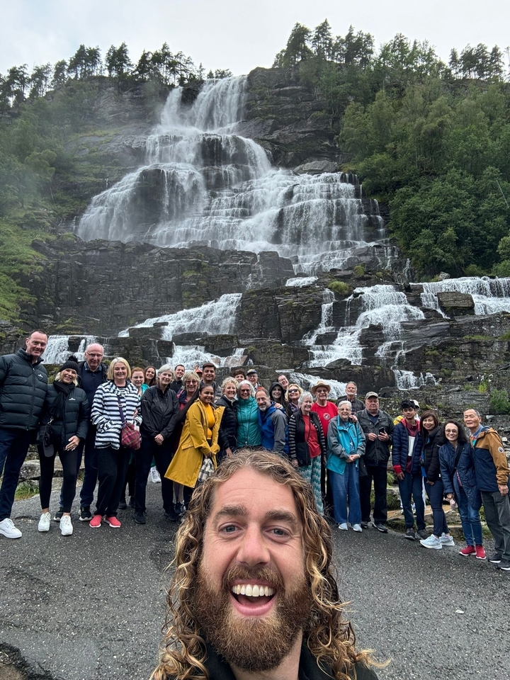 Grand groupe de personnes debout devant une grande cascade.