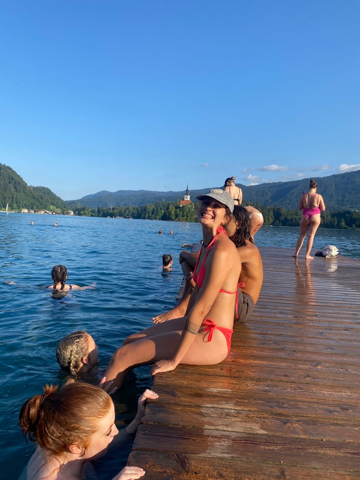 Des gens qui se détendent au bord d'un lac avec des montagnes en arrière-plan.