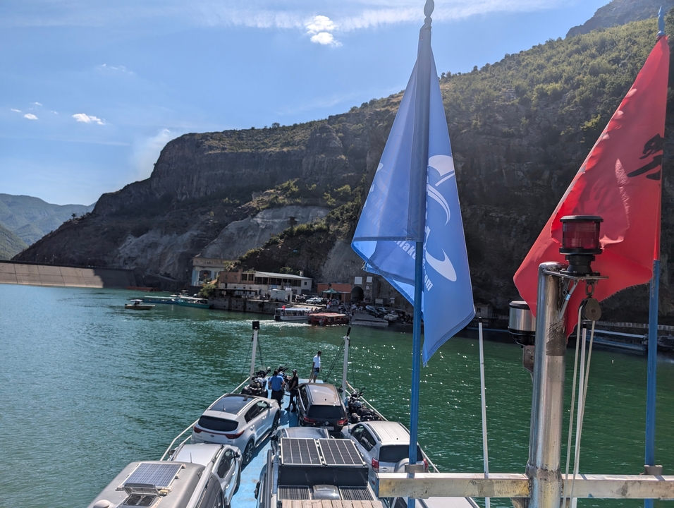 Promenade en bateau avec drapeaux surplombant un littoral montagneux