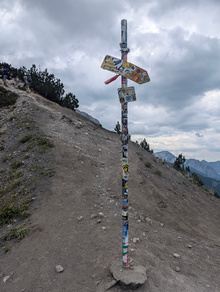 Panneau indicateur de sentier couvert d'autocollants dans une région montagneuse