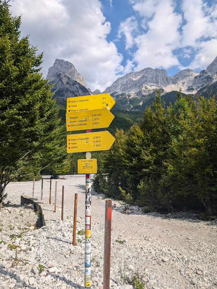 Panneaux de randonnée directionnels jaunes sur un fond montagneux.