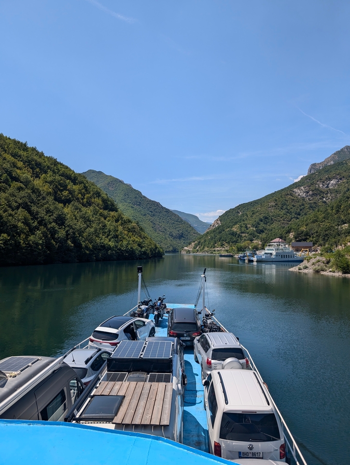 Vue panoramique d'une rivière bordée de montagnes, avec des bateaux sur l'eau.