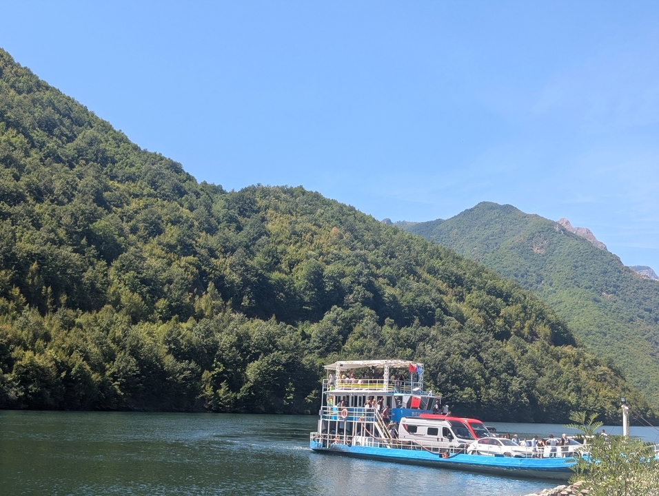 Bateau d'excursion avec des passagers sur une rivière entourée de montagnes boisées.