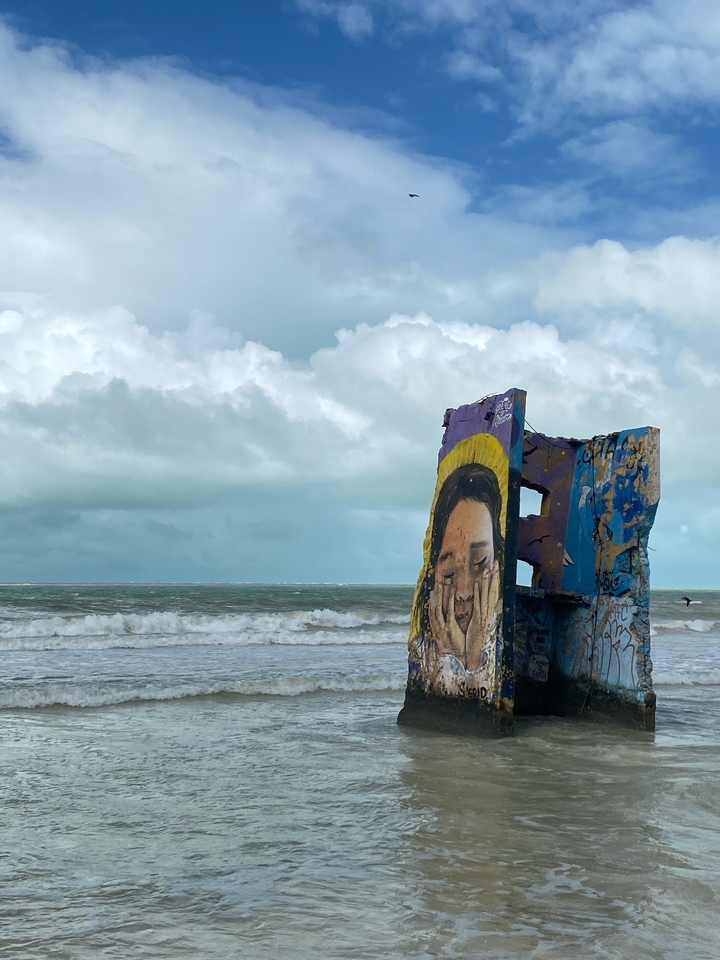 Plage avec dalle de béton tagguée et vagues de l'océan.
