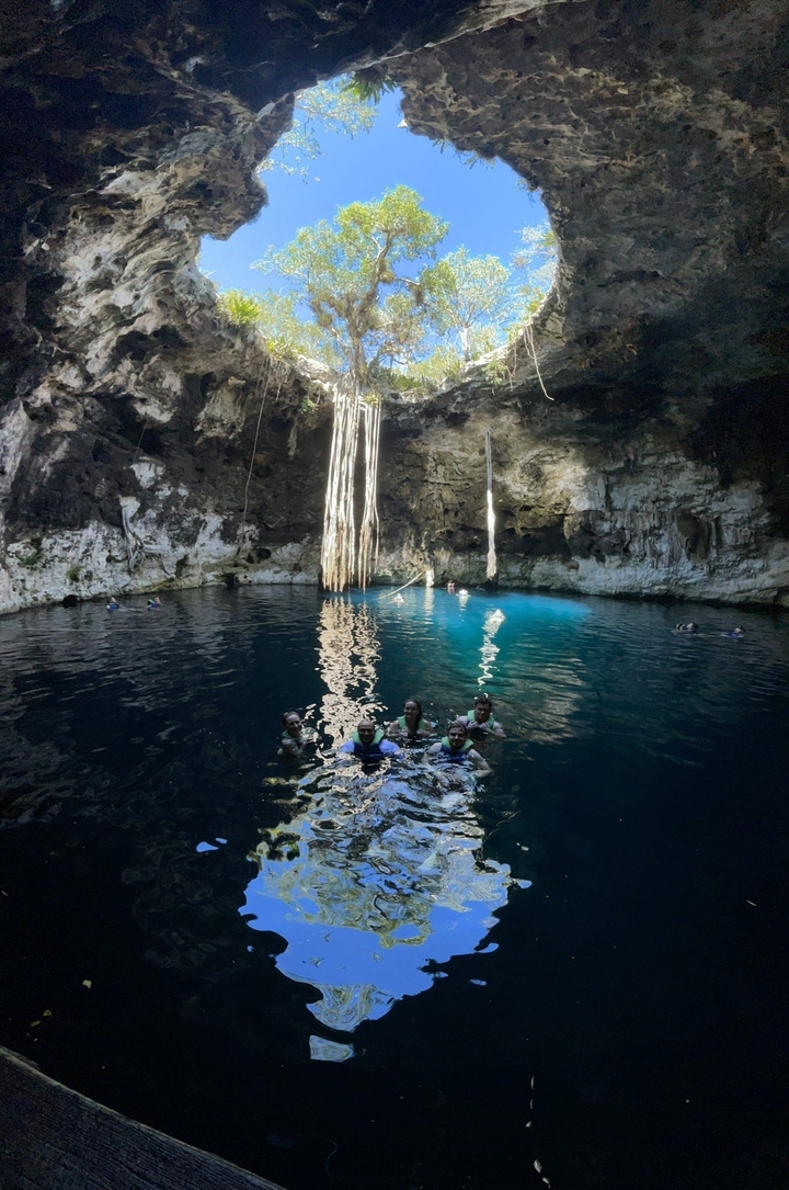 Des gens qui nagent dans un cénote bleu cristallin.