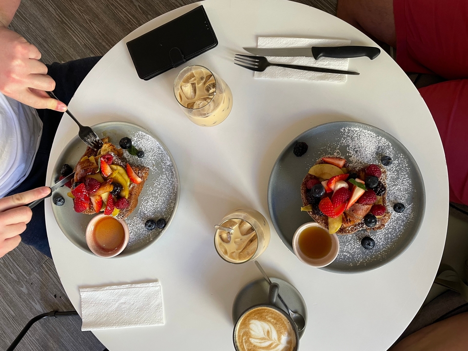 Deux assiettes avec des gaufres garnies de fruits et du café glacé sur une table.