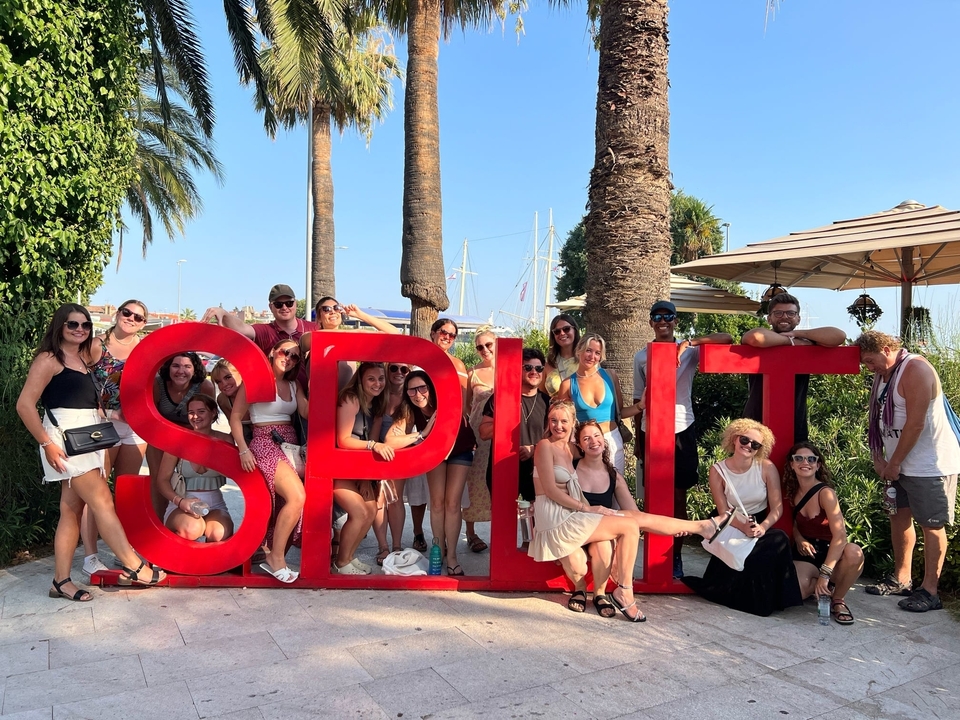 Large group of people posing with 'SPLIT' sign.
