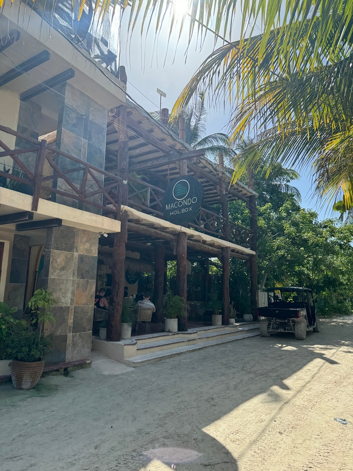 Restaurant nommé 'MACONDO HOLBOX' avec des gens assis dehors.