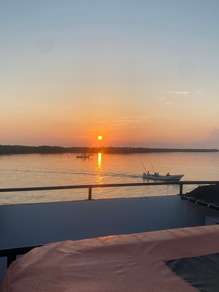 Bateau naviguant pendant un coucher de soleil doré sur des eaux calmes.