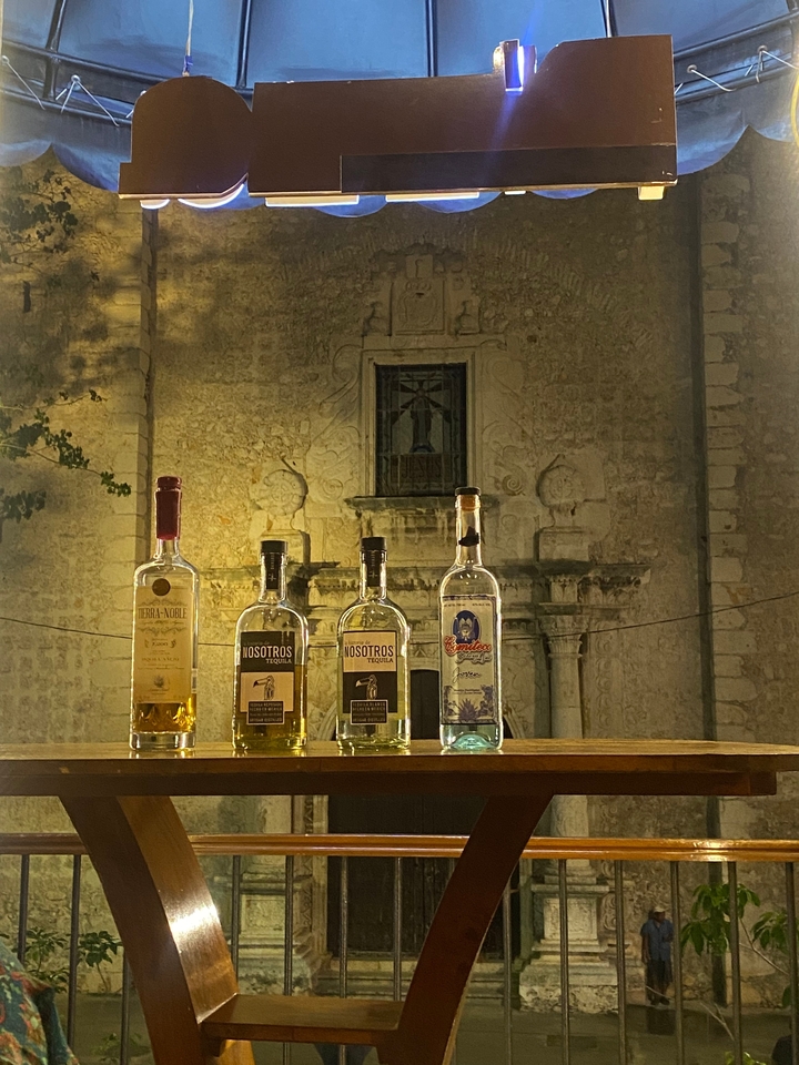 Bouteilles de tequila exposées la nuit devant un bâtiment historique.