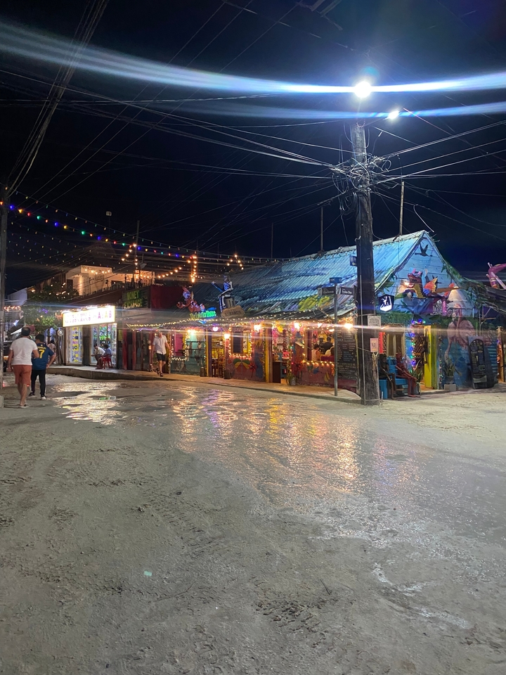 Scène de rue colorée la nuit avec des magasins et des lumières.