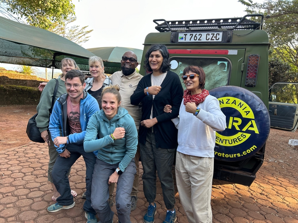 Groupe de voyageurs posant devant un véhicule de safari.