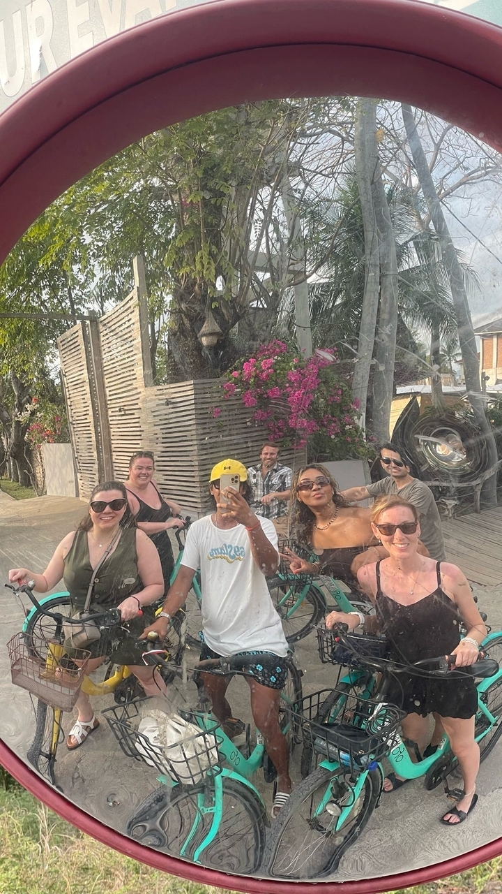 Photo de groupe prise à travers une surface réfléchissante, montrant des personnes posant joyeusement.