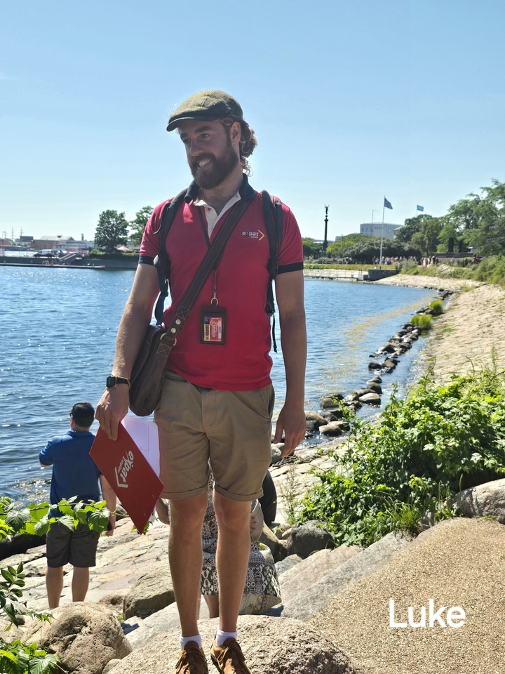 Un homme debout au bord d'une rivière, tenant une brochure de voyage.