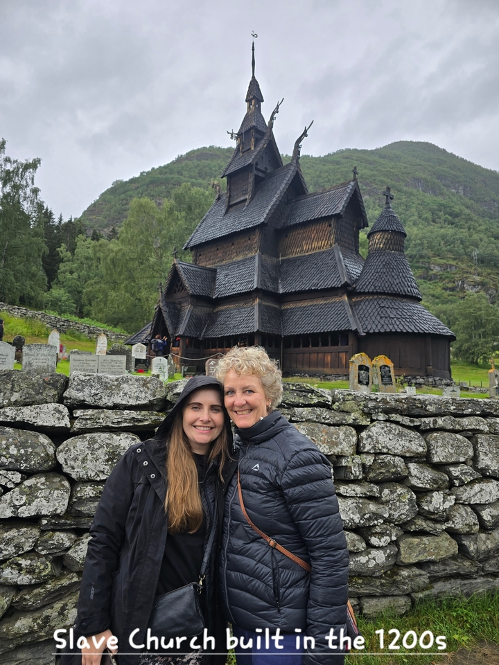 Deux femmes posant devant une église traditionnelle à l'architecture en bois.