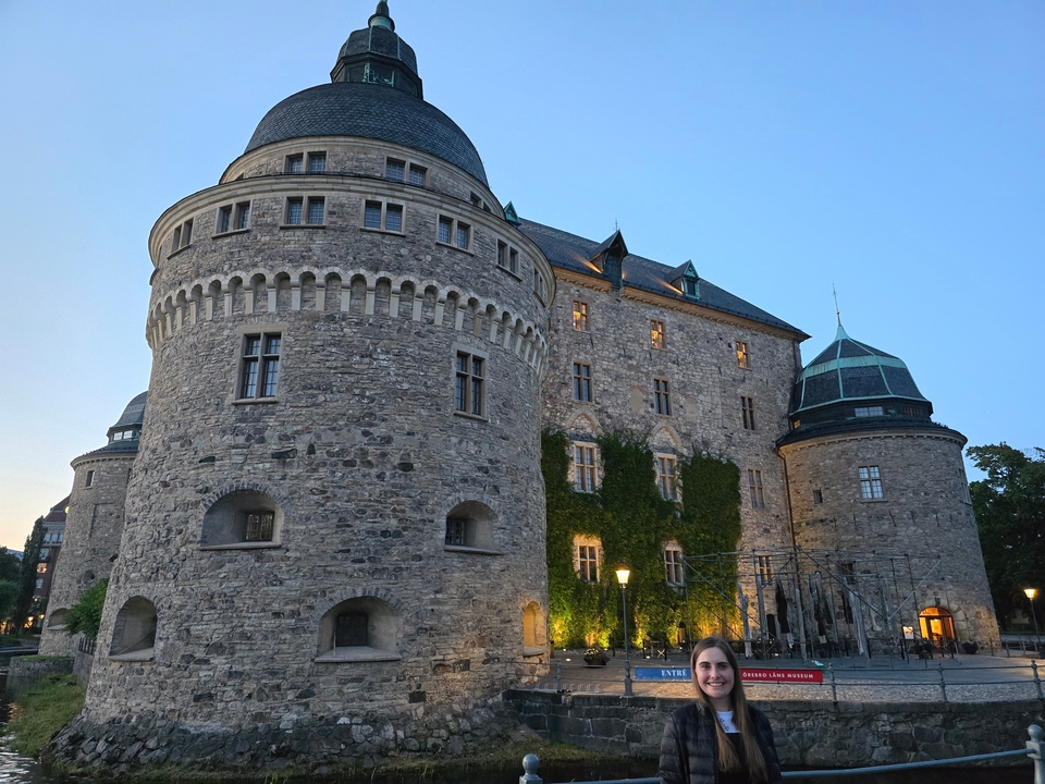 Un grand château de pierre avec des tours rondes, éclairé par la lumière du début de soirée.