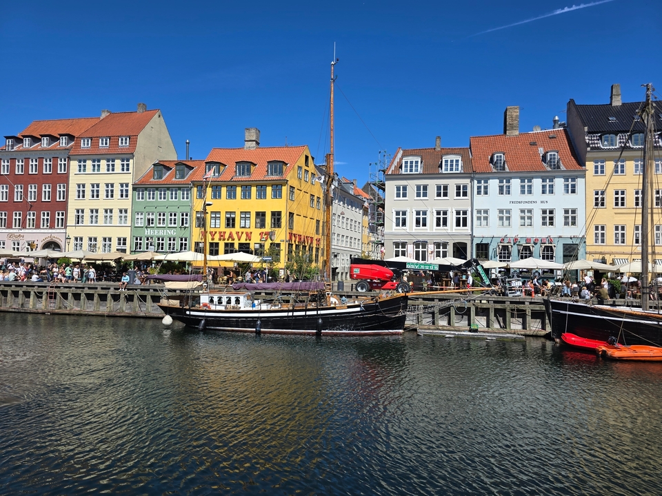 Bâtiments historiques colorés bordant un front de mer avec des bateaux amarrés le long de la rivière.