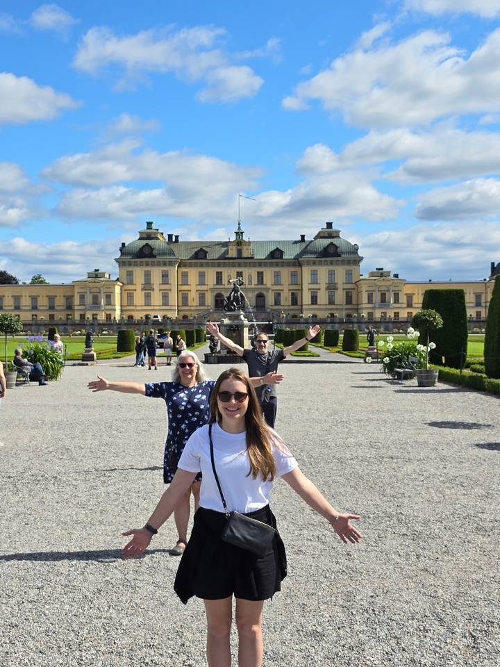 Un groupe de personnes posant devant un grand bâtiment historique.