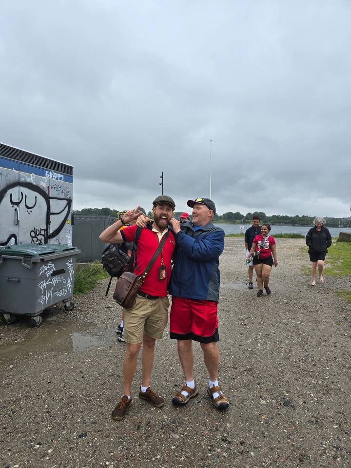 Deux hommes posant avec un geste enjoué près d'un plan d'eau.