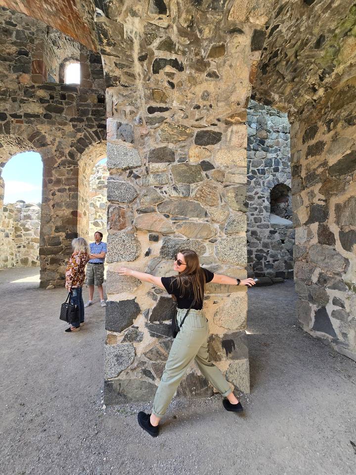 Des gens explorant d'anciennes ruines de pierre avec des arches et des piliers.