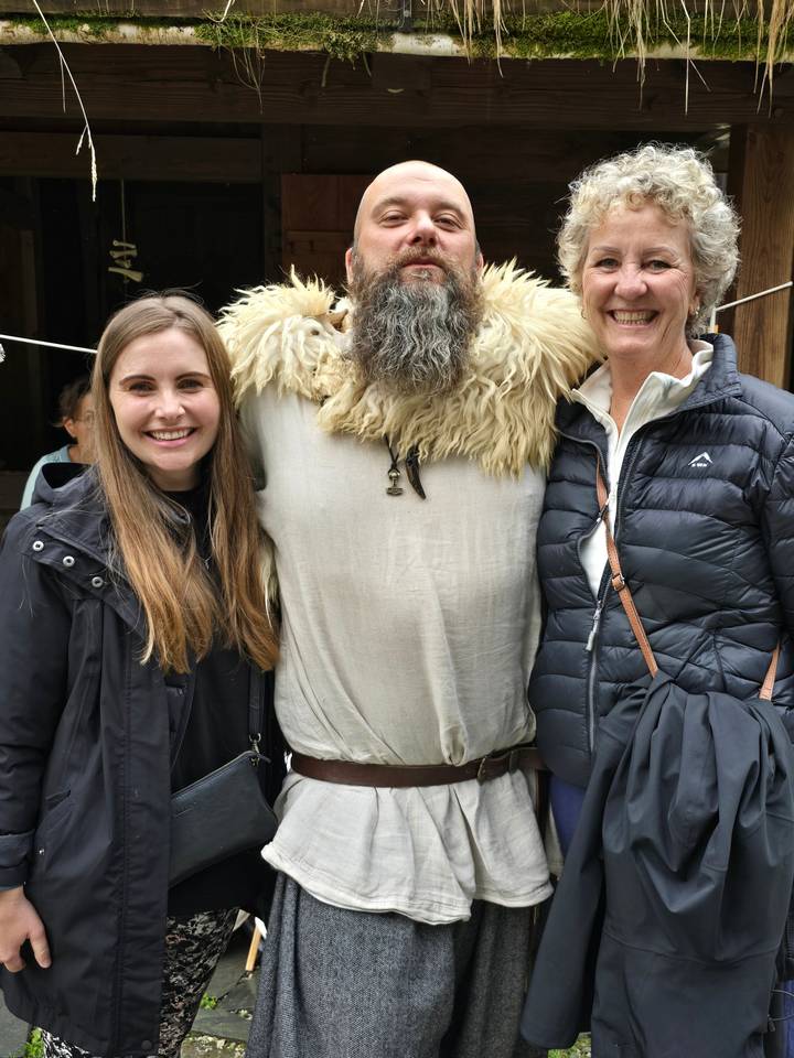 Deux femmes posant avec une personne en tenue traditionnelle.