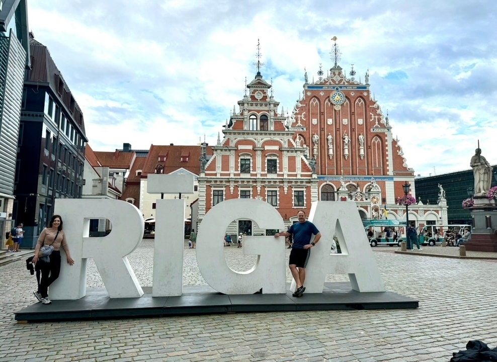 Grandes lettres d'enseigne épelant 'RIGA' avec des bâtiments historiques.