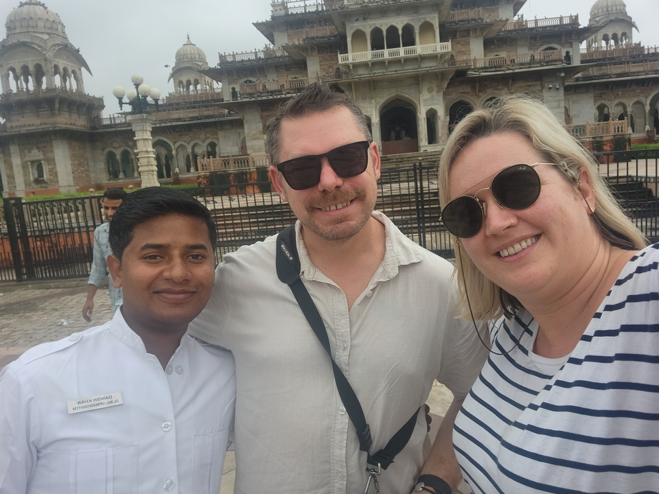 Trois personnes souriant devant un bâtiment historique.