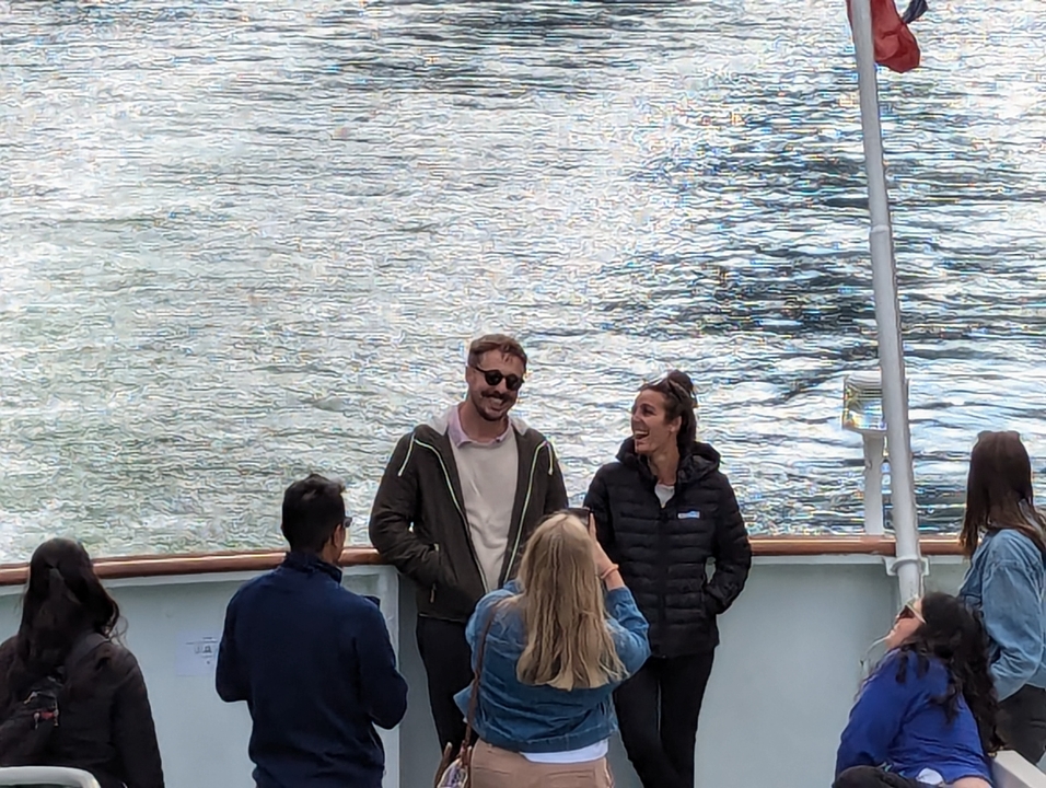 People standing on a boat with scenic water views.