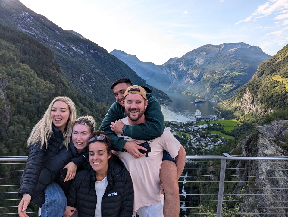 Group of friends posing with mountain and water views.