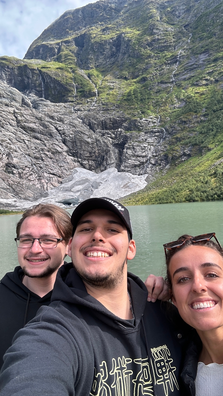 Trois personnes souriantes avec en arrière-plan une montagne rocheuse et un lac.