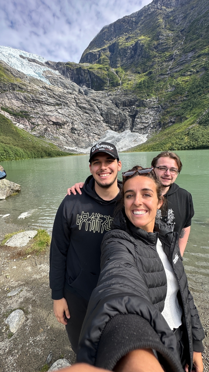 Trois personnes souriantes avec en arrière-plan une montagne rocheuse et un lac.