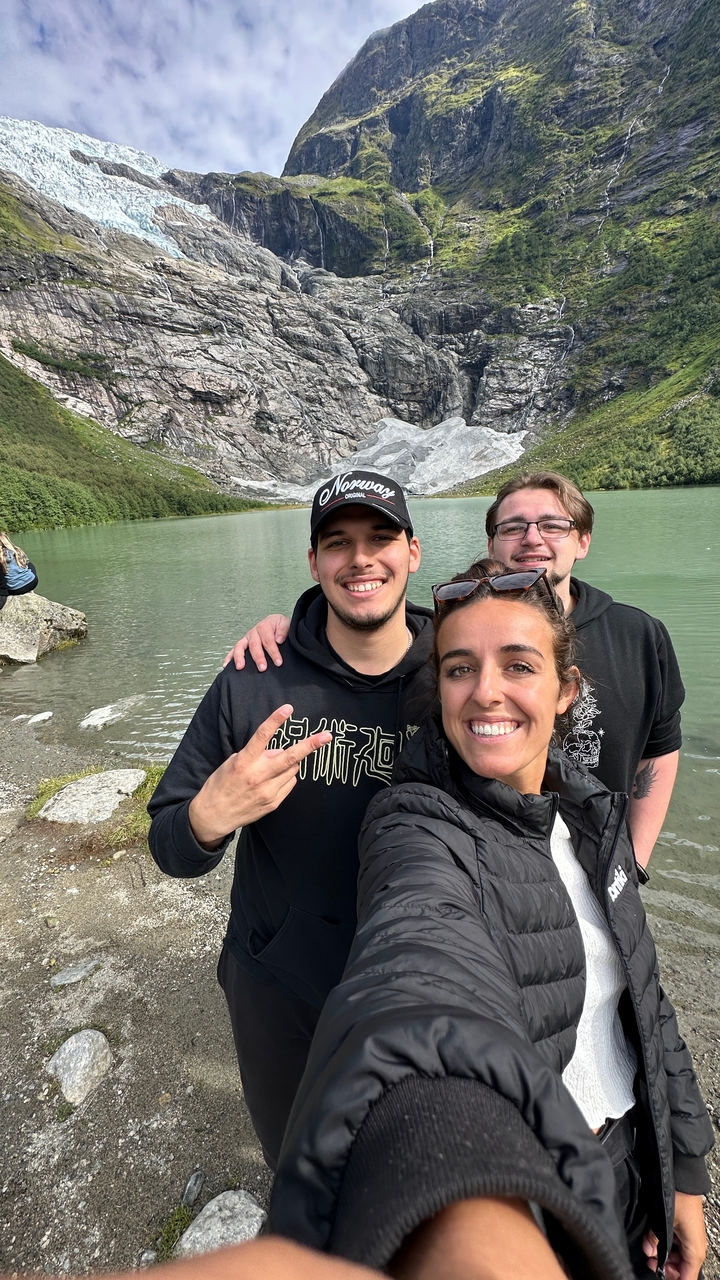Trois personnes souriantes avec en arrière-plan une montagne rocheuse et un lac.