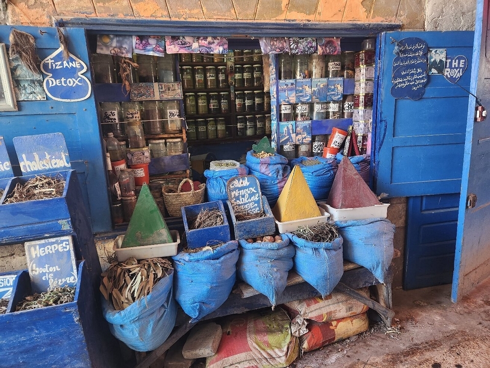 Devanture colorée avec des sacs et des herbes exposés dans la rue.