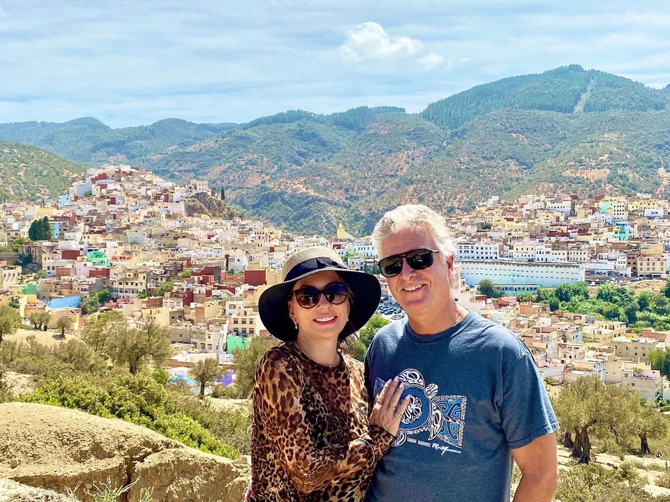 Un couple posant devant une vue panoramique d'une ville entourée de collines.