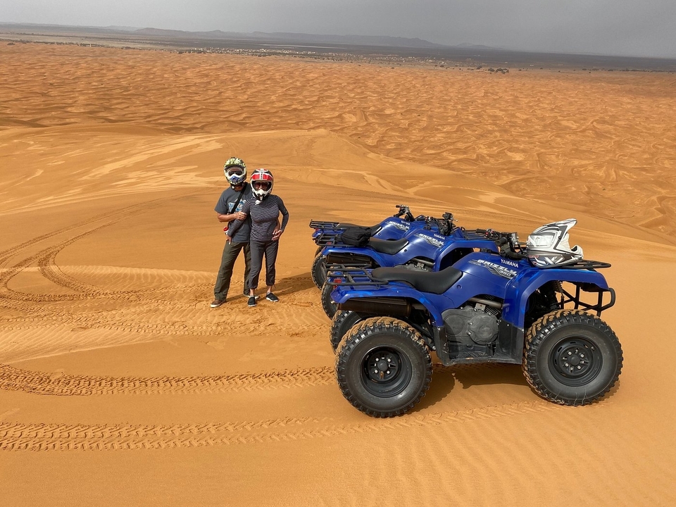 Un couple posant avec des VTT dans les dunes de sable.