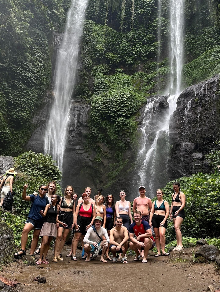 Group of people posing in front of a waterfall.