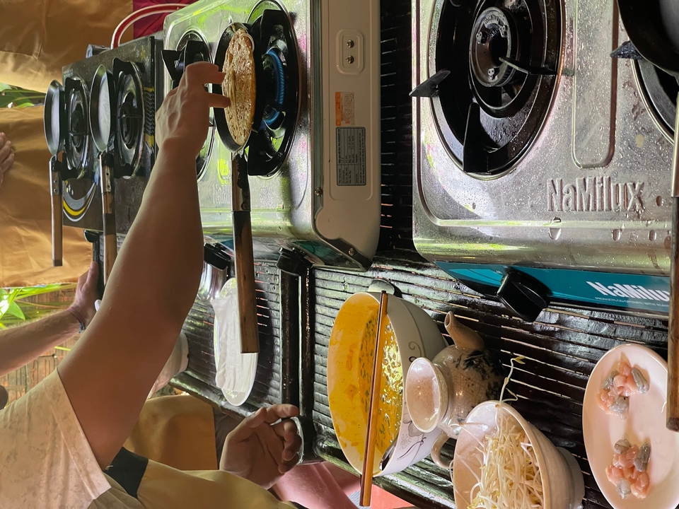 Des gens cuisinant sur des réchauds dans un aménagement extérieur.