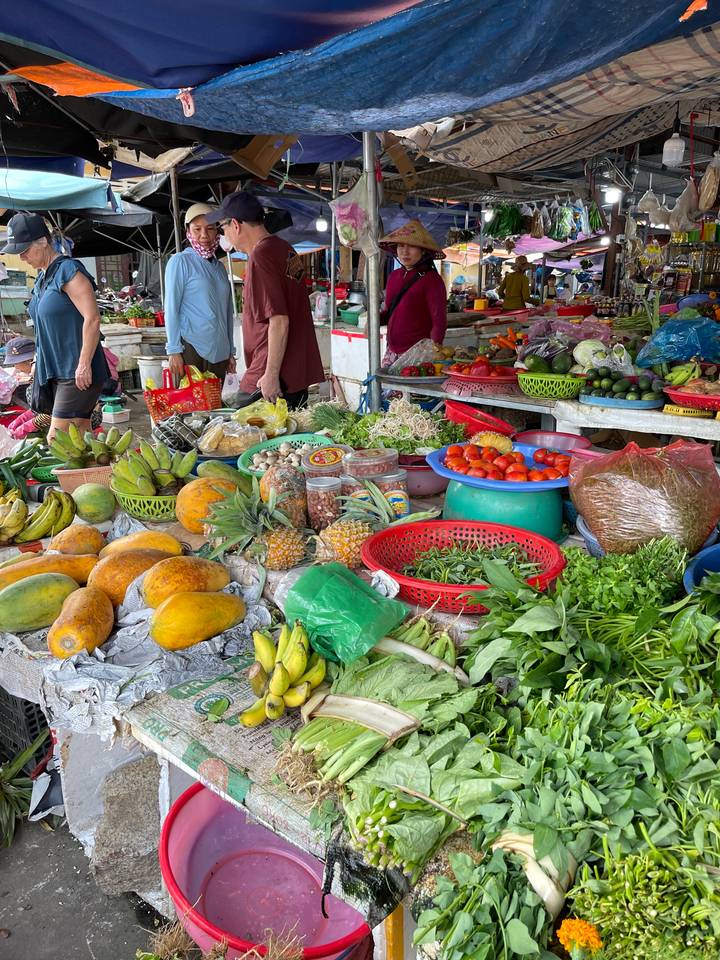 Étal de marché avec divers fruits et légumes exposés.