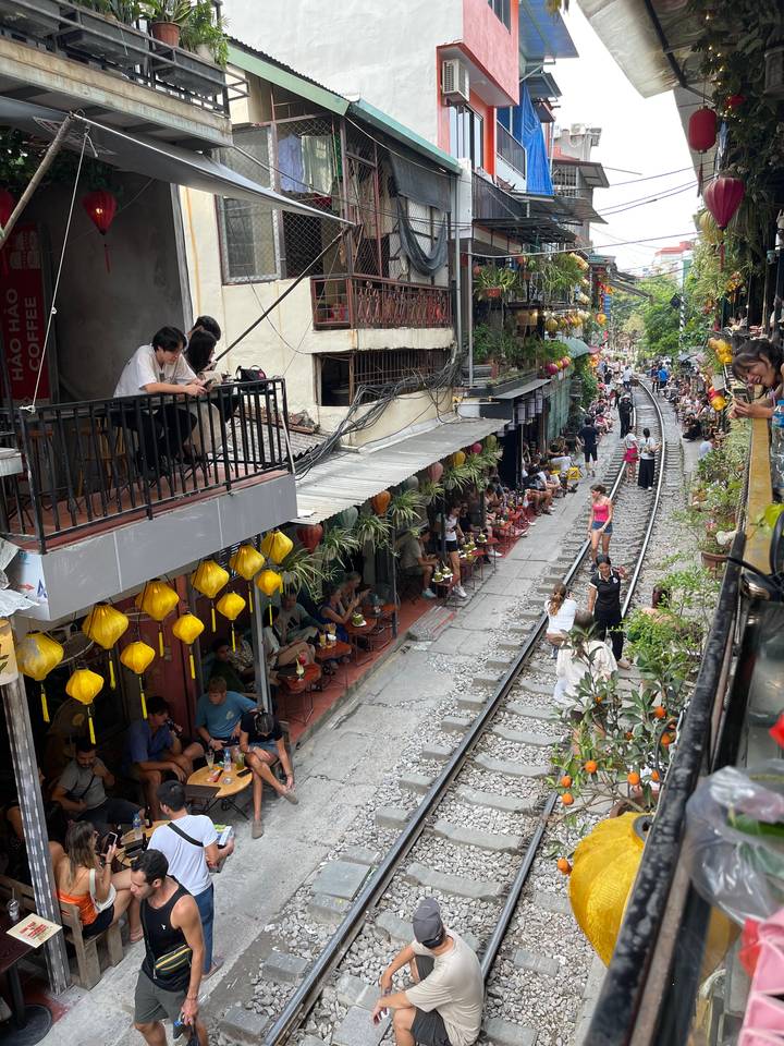 Des voies ferrées traversant un marché de rue animé avec des gens qui dînent.