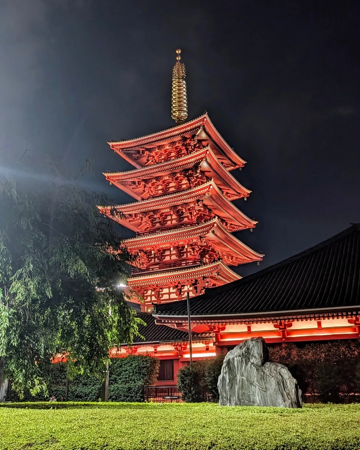 Pagode illuminée la nuit avec un ciel dramatique.