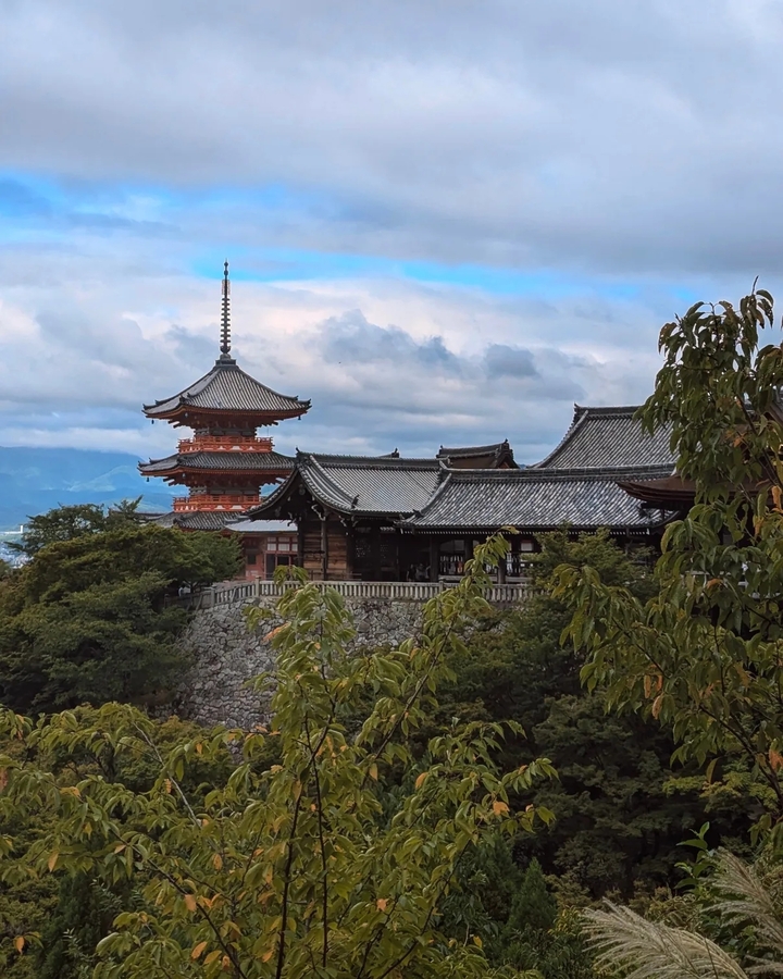 Complexe de temple avec une pagode entourée d'arbres et de montagnes.
