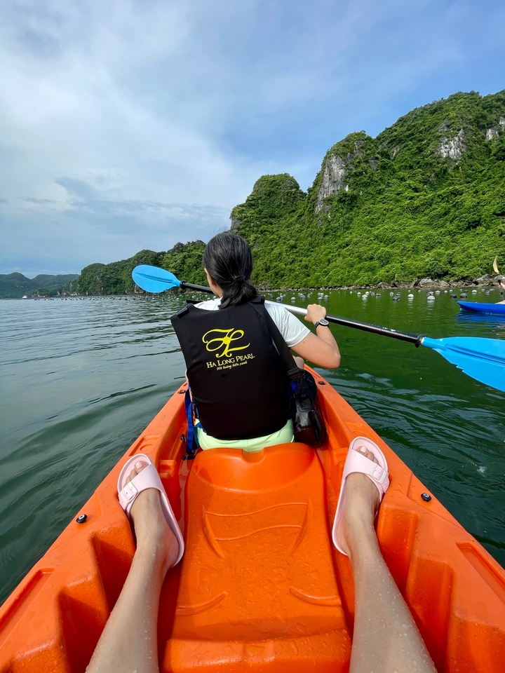 Personne faisant du kayak dans un plan d'eau avec des collines verdoyantes en arrière-plan.