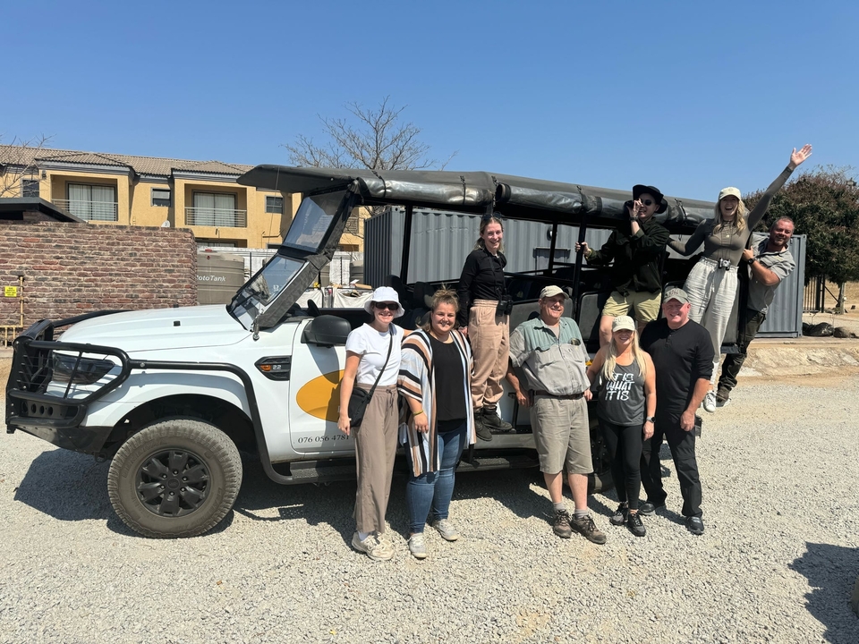 Groupe de personnes posant à côté d'un véhicule de safari.