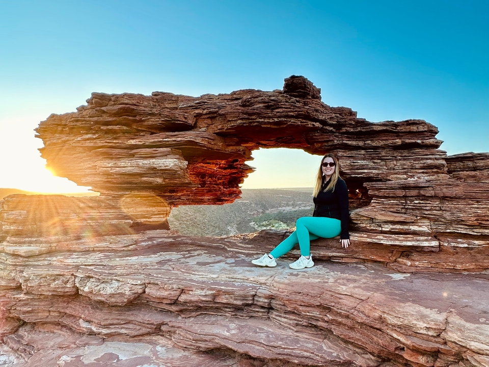 Personne assise dans une formation rocheuse avec la lumière du soleil.