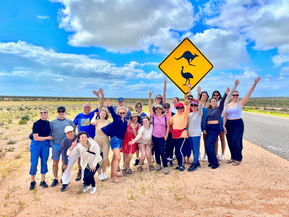 Groupe de personnes posant à côté d'un panneau routier avec des symboles d'animaux.