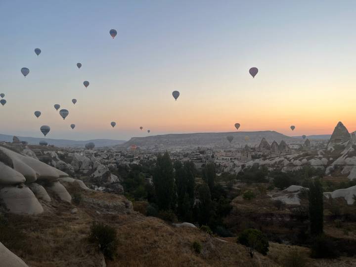 Montgolfières flottant au-dessus d'un paysage rocheux au coucher du soleil.