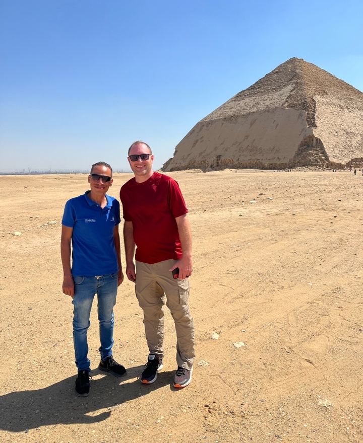 Deux personnes posant devant une pyramide avec une vue étendue sur le désert.