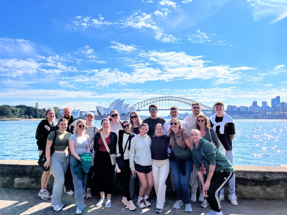 Grande groupe devant l'Opéra de Sydney et le Harbour Bridge